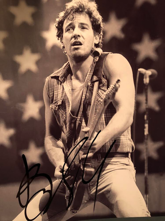 This image display Bruce Springsteen performing at an concert.  This photo has been signed by The Boss himself Bruce Springsteen.